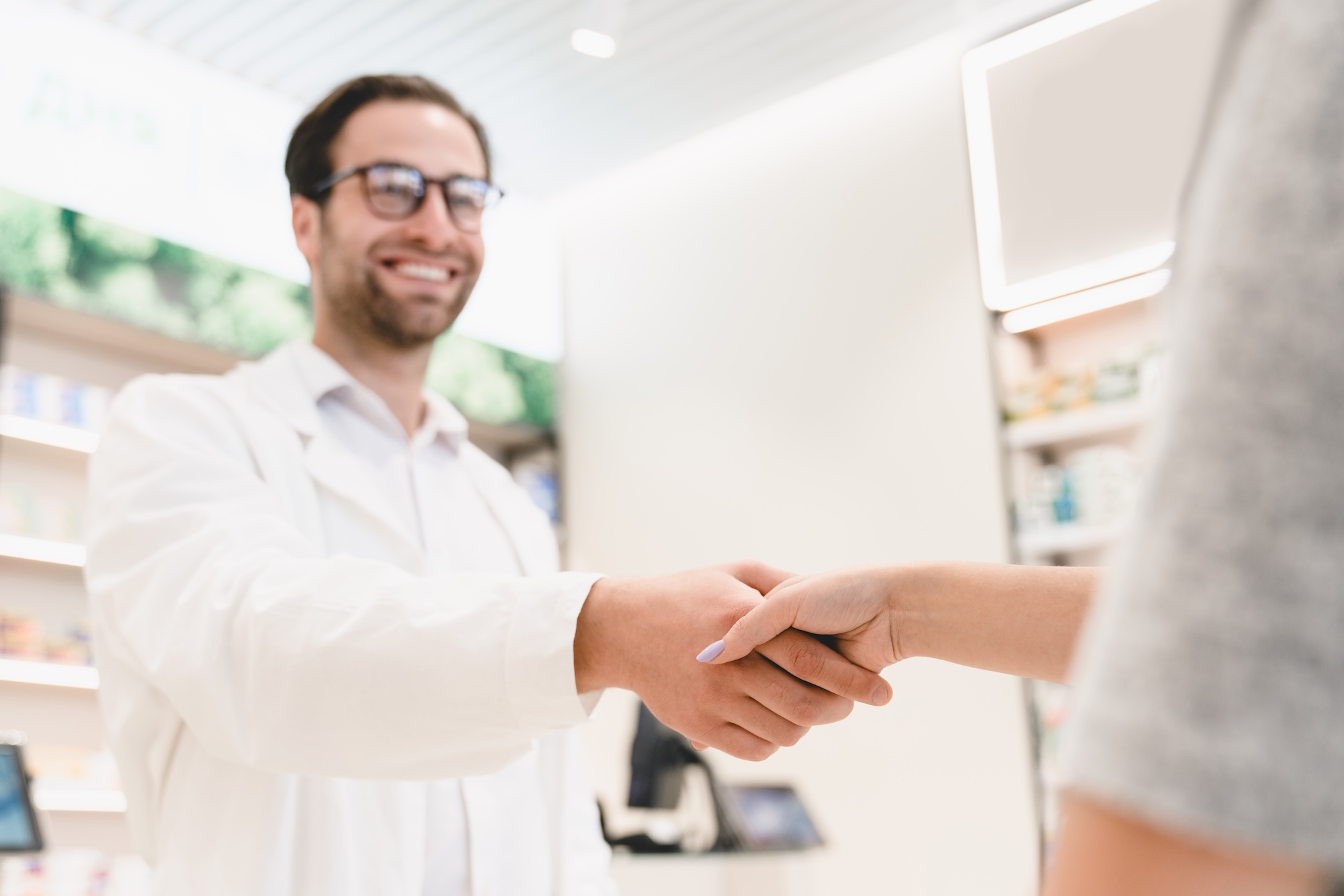 druggist shaking customer hand while buying drugs, painkillers, medicines in pharmacy drugstore